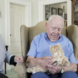 An animatronic cat is presented to an elderly man.